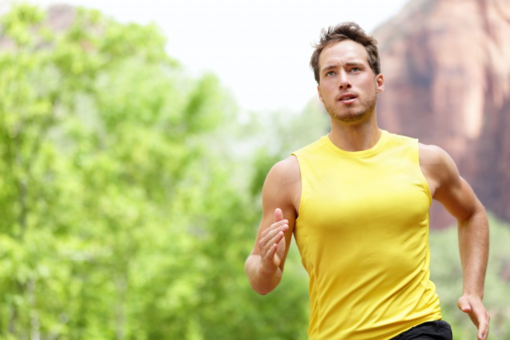 Sport - Runner. Man running with concentration, determination and strength towards goals and success in marathon. Fit male sport fitness model sprinting outdoors.